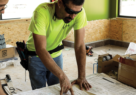 Electrician Devon Turner reviews blueprints for a Popeyes location in Blairsville, GA. Myriad Electrical Contractors is Prime Retail Services’ electrical division, which serves the southeastern United States.  