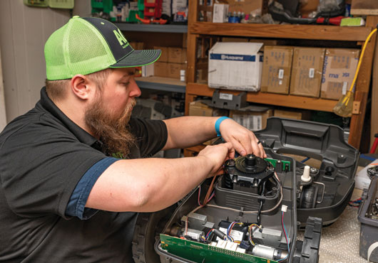 Mobile Service Technician Alex Schanna fixes a loop sensor on a Husqvarna Automower 315X.