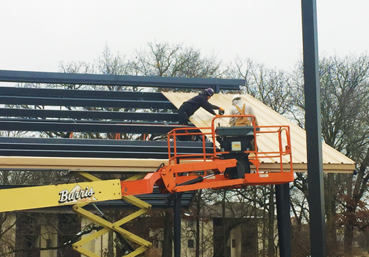 Tim Johannsen, left, and Orlando Diaz, employees of Lake Shore Construction Inc., work on adding the roof panels to the pavilion.