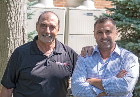 Jeff Mitchell, left, Vice President/service manager, and Zack Mitchell, President, chose the Variable Refrigerant Flow (VRF) system shown in the background for the company’s offices in Westlake, Ohio. Westland Heating & Air Conditioning is a leader in VRF technology and one of a few contractors able to offer this high-efficiency system.