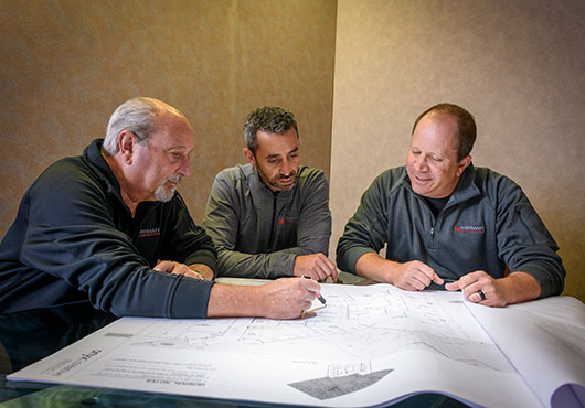 Left to right: Mirman Construction Founder and CEO Keith Mirman reviews blueprints with President Brett Mirman and Executive Vice President Andrew Mirman.