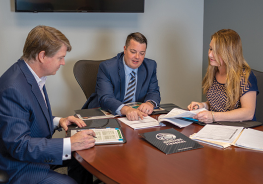 Founding Managing Partner Joe Lombardi (center) consults with his wife and Office Manager, Stephanie Lombardi, and Master Broker Timothy Maloney prior to a client meeting.