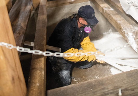OPC Pest Services Certified Technician Bo Williams applies lime in a bourbon barrel warehouse for moisture control.