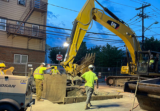 The crews at American Underground Construction, LLC work on a 15-inch sanitary connection that taps into a 60-inch cast iron pipe 23 feet underground. This required extensive excavation of contaminated materials and trench boxing, all in the middle of a busy intersection. 