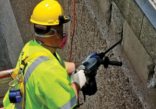 LJS Waterproofing LLC’s Project Manager Lou Marques Jr. chips through concrete to recoat rusted rebar with an anti-corrosion chemical before repairing the concrete at the Rockaway Wastewater Treatment Plant.