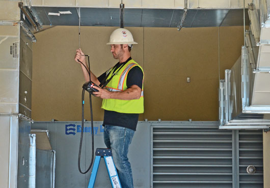 Technician Kevin Weir takes a duct traverse reading of the air flow. 