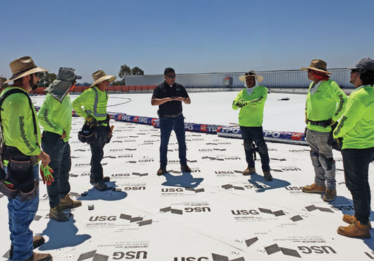 Vice President Hector Gutierrez (center) holds a rooftop meeting with the Shell Roofing Solutions Group crew to discuss safety issues and the new roofing system installation.