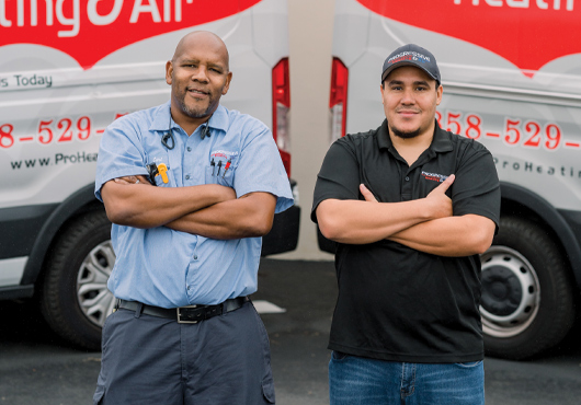 Carl Johnson (left), Part-Owner and Field Service Supervisor of Progressive Heating & Air Inc., and Adrian Alvarez, Founder and President of Progressive, stand proudly before Progressive’s company trucks parked at the company’s office in San Diego.
