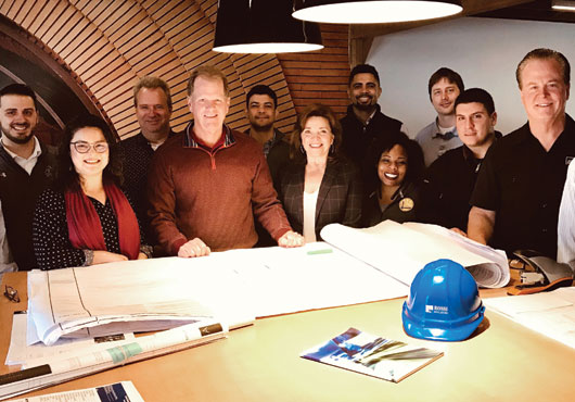 Carol Ann (right center), pictured here with Craig Rossi, President (left center), and the Rossi Builders team in their new office. 